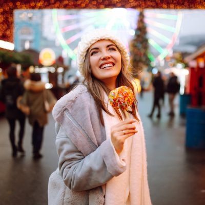 young-woman-with-caramel-apple-on-christmas-market-2022-11-09-04-58-01-utc